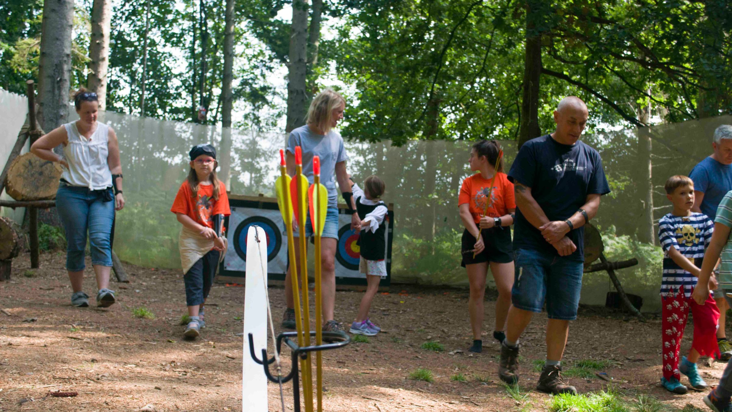 Group of people walking near archery targets in a forest.