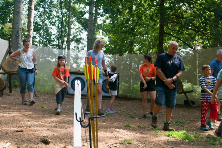 Group of people walking near archery targets in a forest.