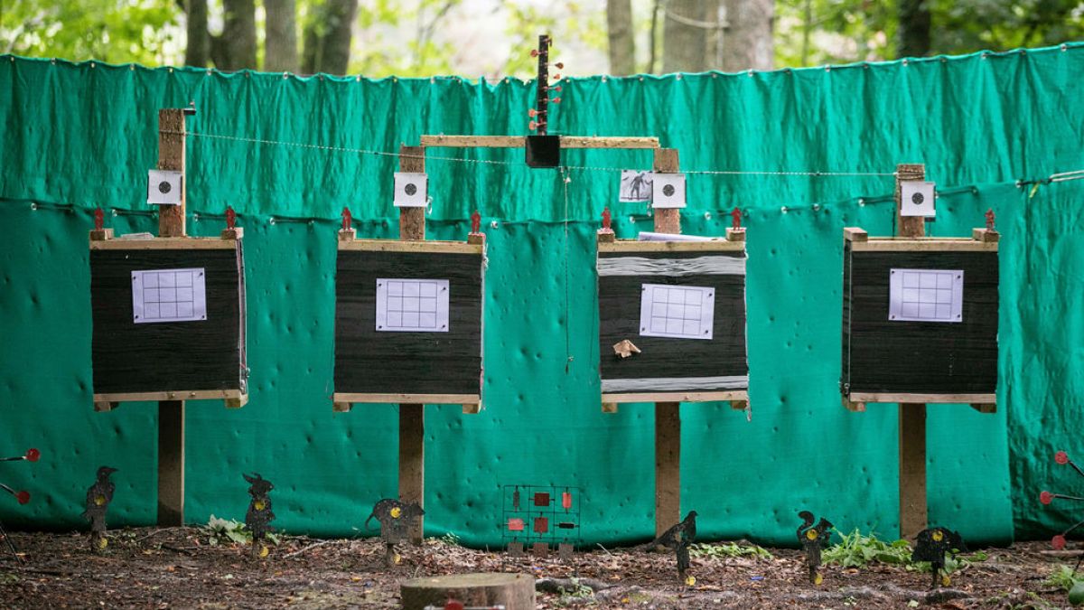 Four archery targets with black and white grid patterns in a wooded area.