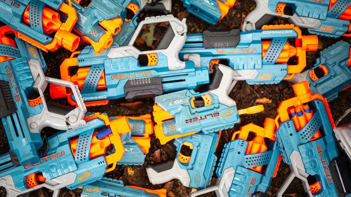 Pile of blue and orange toy Nerf guns labeled 'Elite 2.0' on a dark surface.