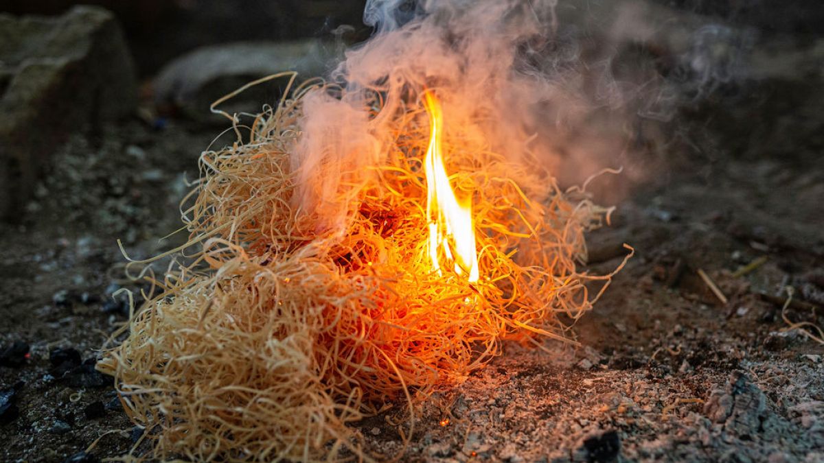 Small fire burning in a pile of dry straw on the ground.