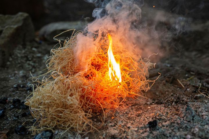Small fire burning in a pile of dry straw on the ground.