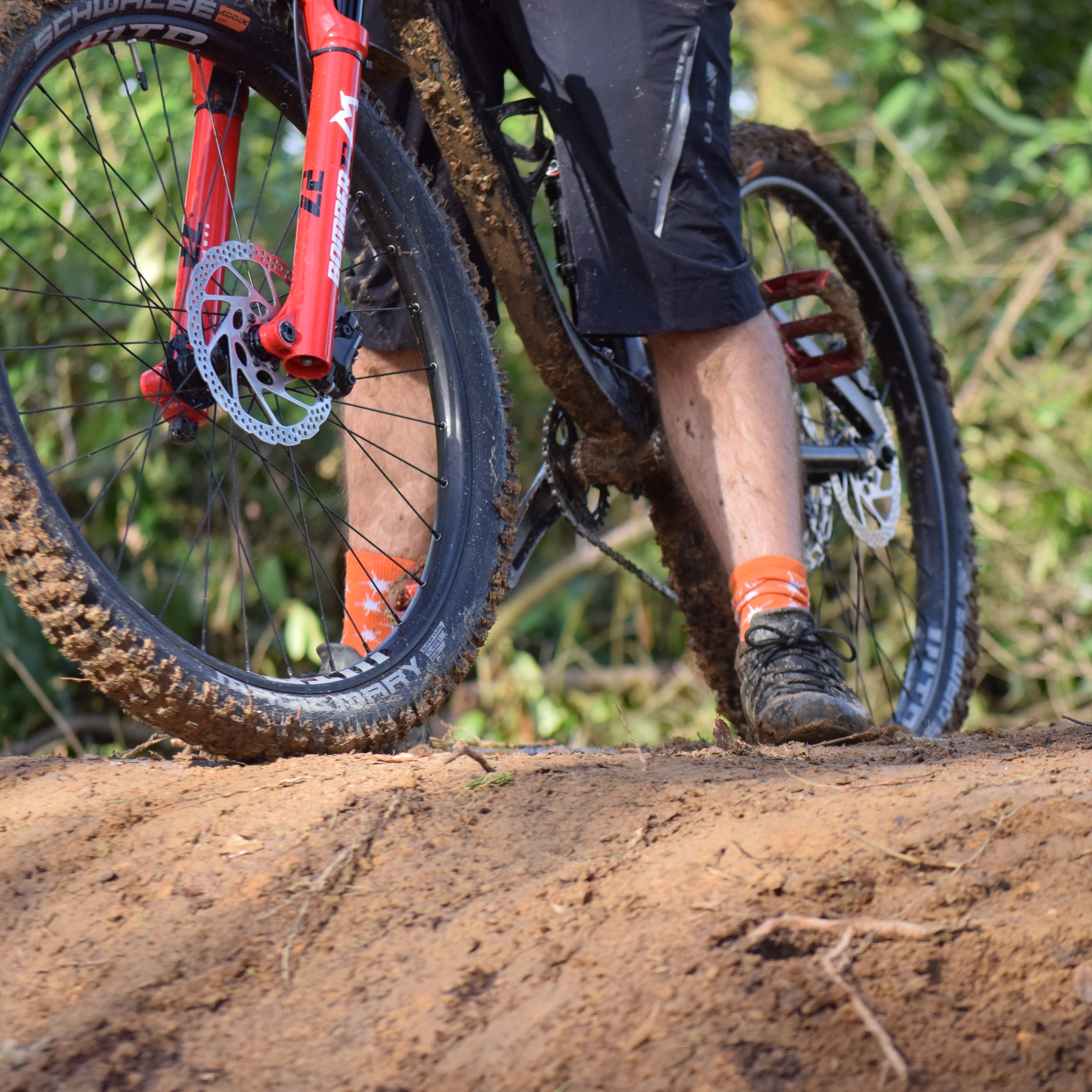 Person riding a mountain bike with muddy tires on a dirt path.