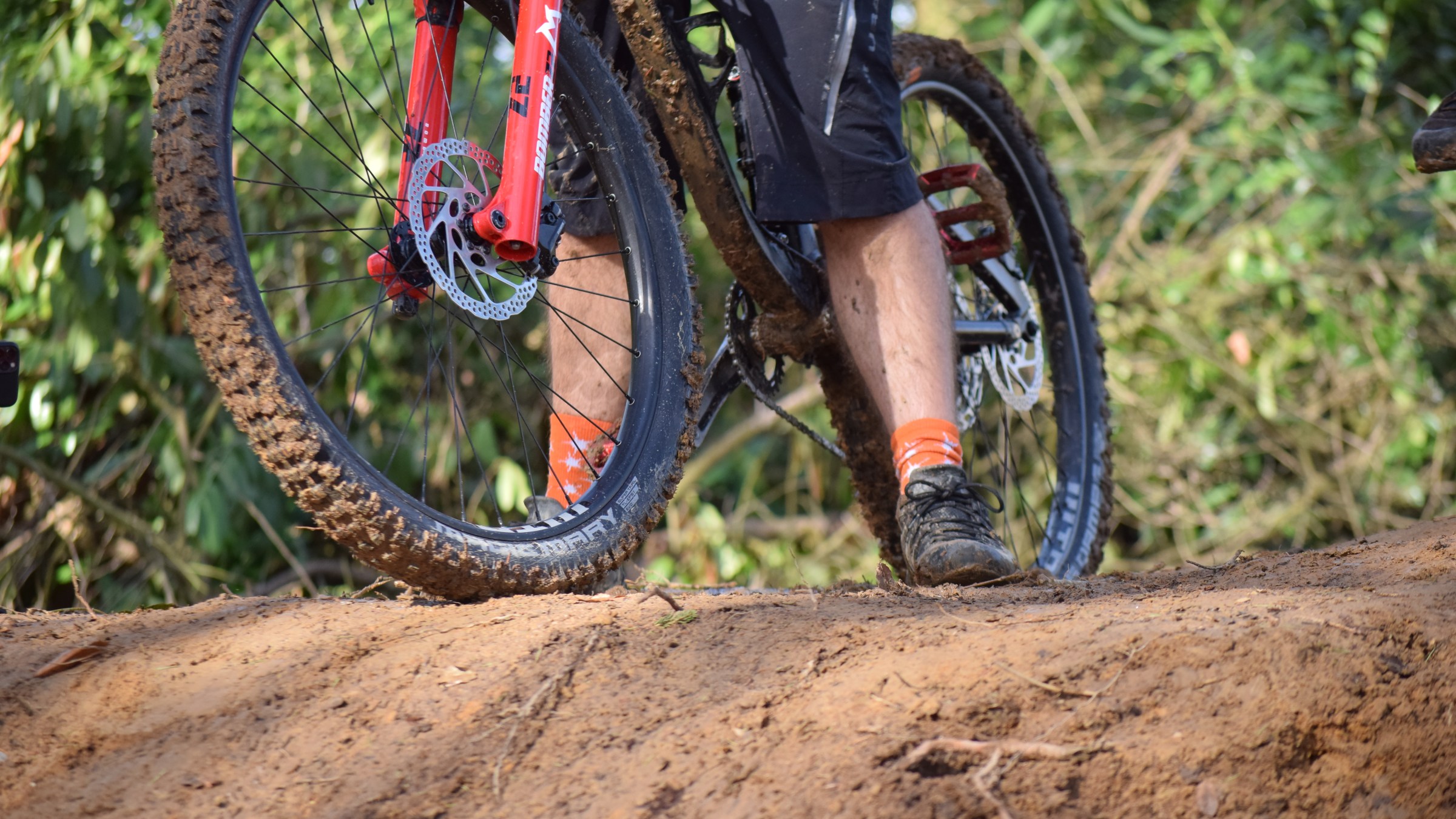 Person riding a mountain bike with muddy tires on a dirt path.