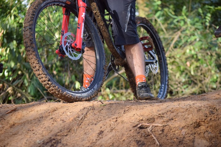 Person riding a mountain bike with muddy tires on a dirt path.