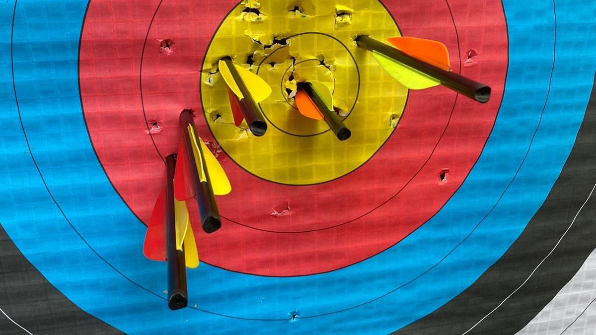 Archery target with multiple arrows hitting the yellow center area.