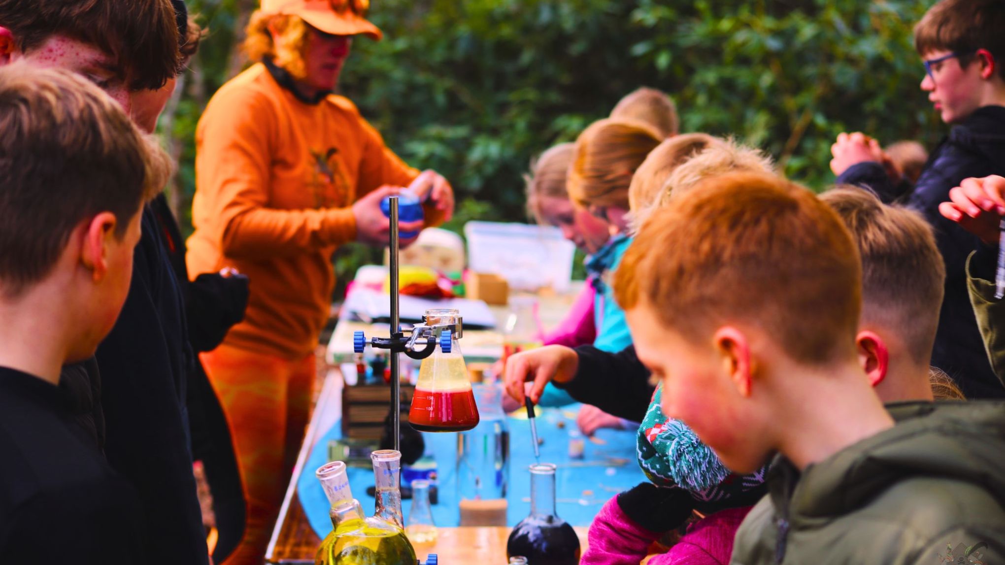 Children engaging in outdoor science experiments with beakers and test tubes.