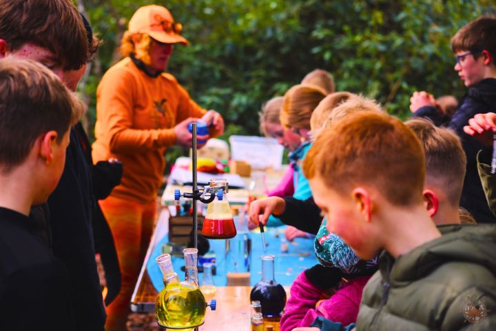 Children engaging in outdoor science experiments with beakers and test tubes.