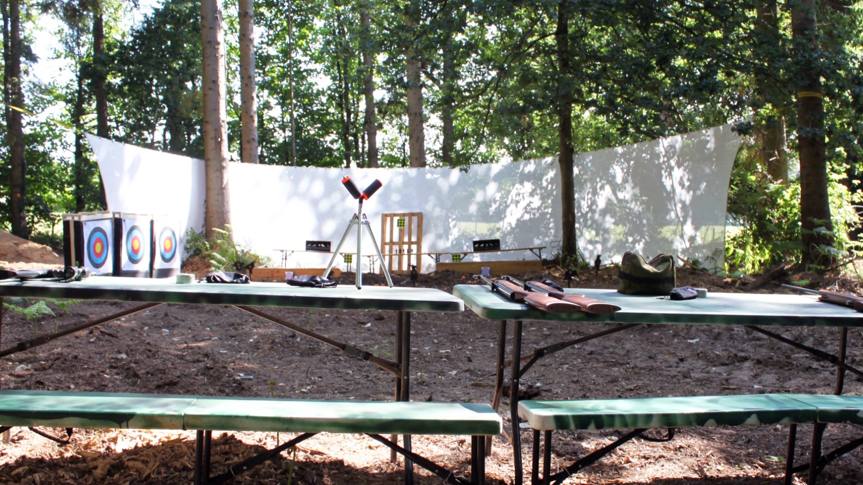 Outdoor archery range with targets and green benches under trees.