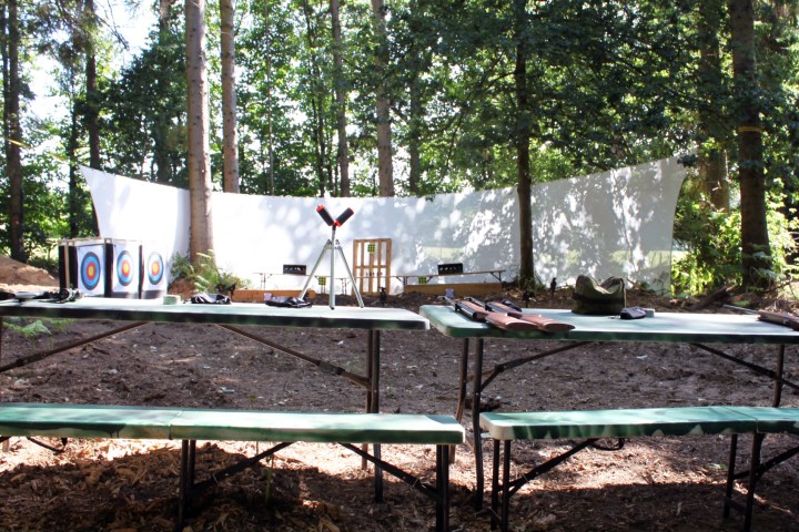 Outdoor archery range with targets and green benches under trees.
